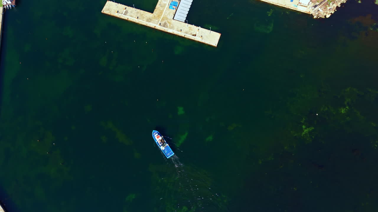 Boat moves through water near dock in afternoon on a calm day in a local harbor