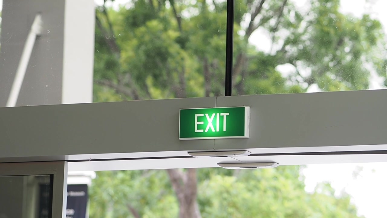 Illuminated Green Exit Sign Above Automatic Glass Doors