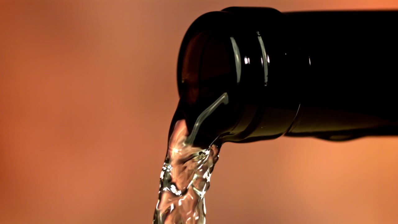 Liquido trasparente versato da una bottiglia scura