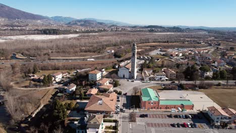 aerial forward view with orbit descending of a church in a village and hills environment