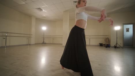 a group of young ballet students in black dancewear practicing positions in a spacious ballet studio with wooden flooring and wall-mounted barres. focused expressions and synchronized movements.