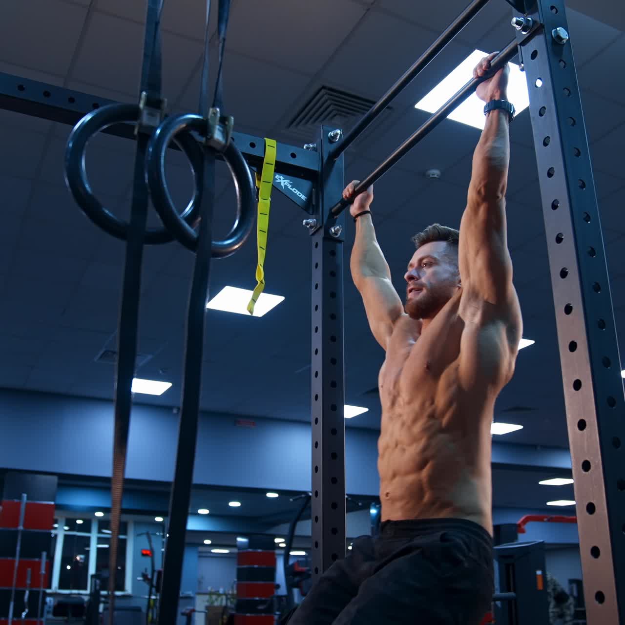 Strong man doing pull ups in gym