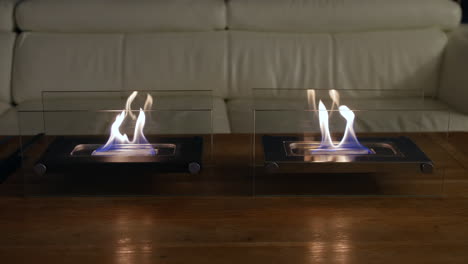 indoor glass fronted fireplaces in a living room on a table with a sofa in the background of the room