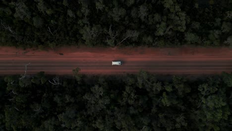 drone top shot of a van driving through australian bush on a red dirt road in western australia