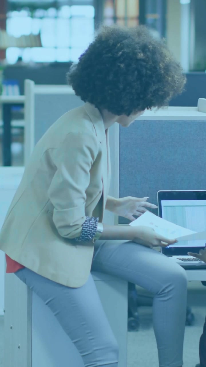 Vertical video: Woman opening doc at desk, tapping laptop, causing binary overlay for tech review