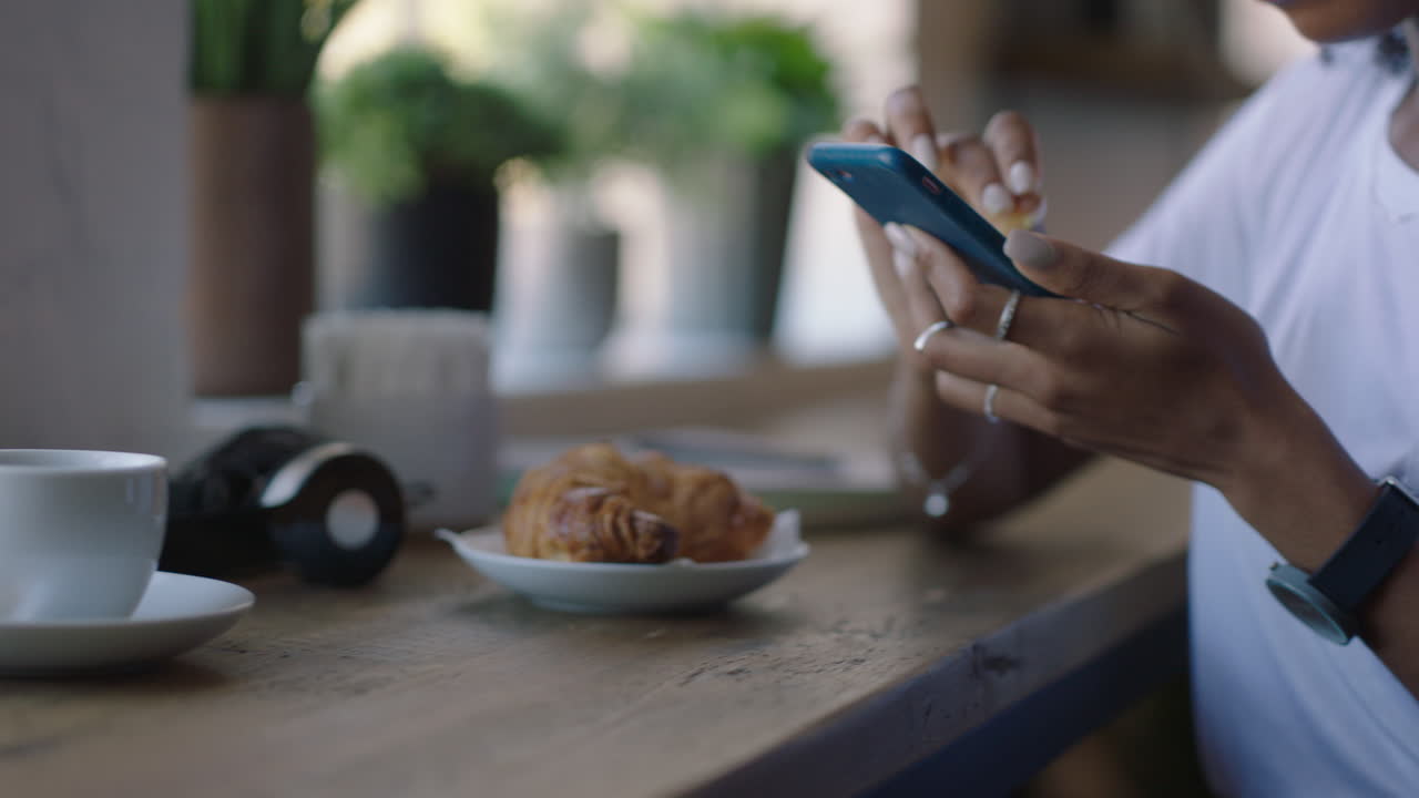 manos de una mujer joven usando un teléfono inteligente en una cafetería bebiendo café navegando por mensajes en línea mujer negra enviando mensajes de texto compartiendo estilo de vida en las redes sociales disfrutando del teléfono móvil de cerca