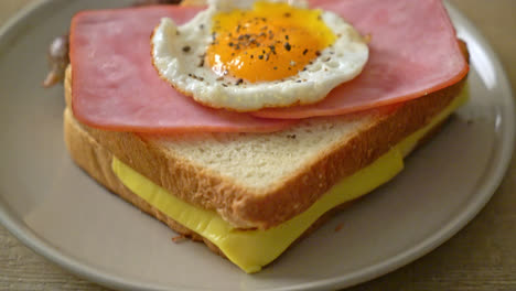 homemade bread toasted cheese topped ham and fried egg with pork sausage for breakfast