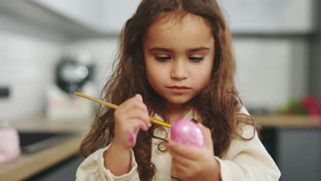child painting easter eggs in the kitchen