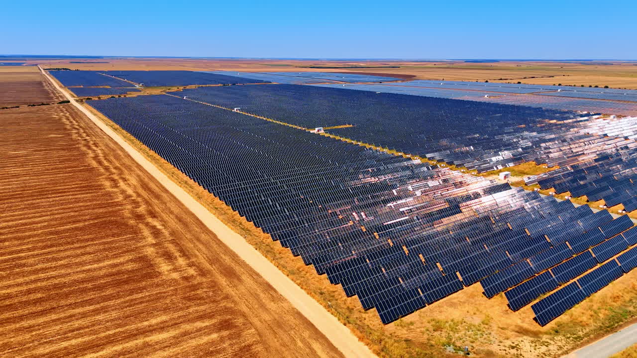 Vast fields of solar panels producing green energy. Drone footage in the rural area on sunny day