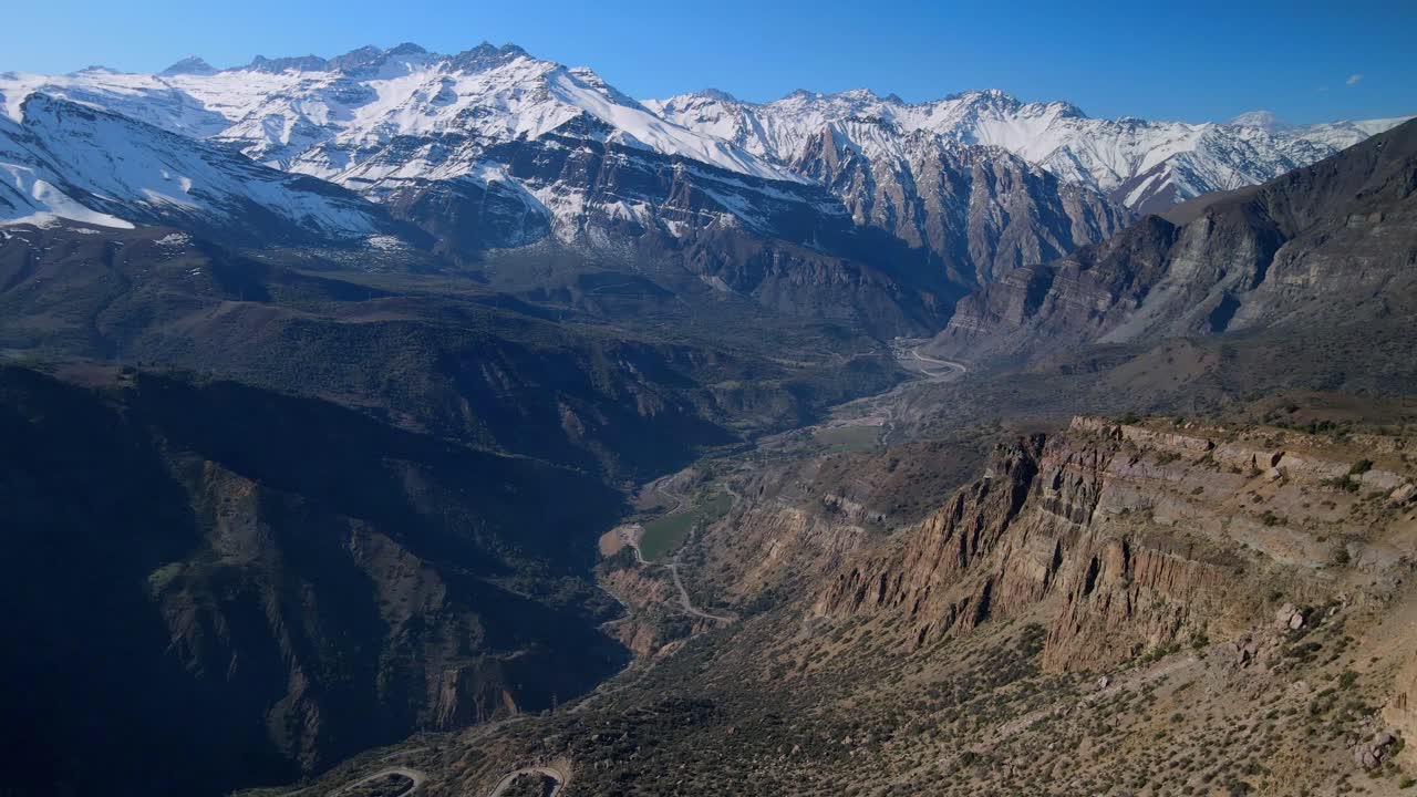 Panoramic view of snow capped mountain range above deep shadowed valleys