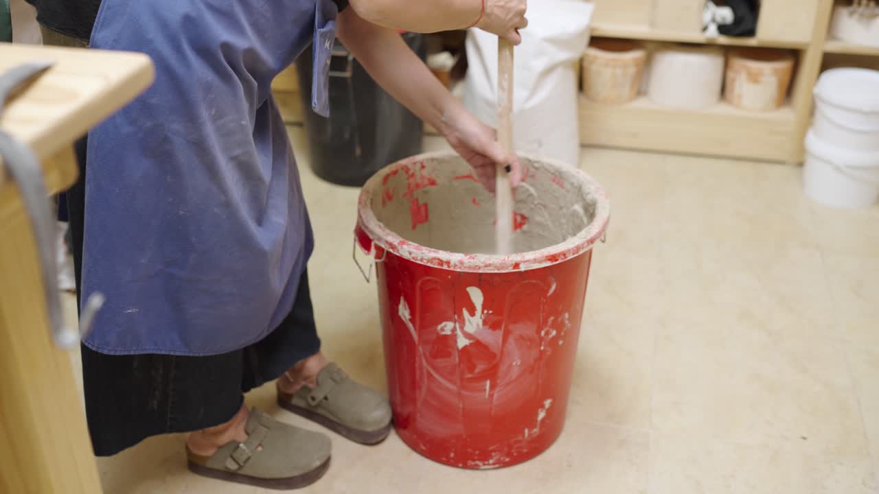 Mixing Clay in a Red Bucket