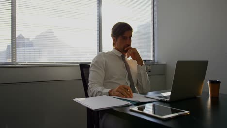 front view of young caucasian male executive working on laptop at desk in a modern office 4k