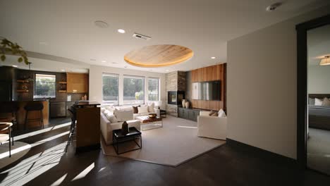 a modern living room with large windows, a stone fireplace, and a wooden ceiling accent, creating a bright and stylish space with a cozy seating area