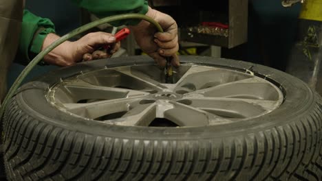 close-up of caucasian hands of a mechanic inflating a car wheel