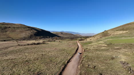 Toma-De-Un-Dron-De-Un-Automóvil-Conduciendo-Por-Un-Camino-De-Tierra-En-Willcox,-Arizona,-Toma-Aérea-Amplia-Con-Montañas-En-El-Fondo