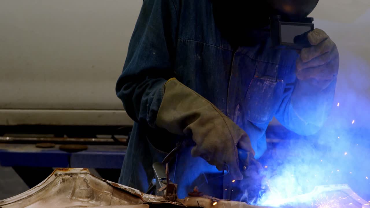 Mechanic using wielding torch on a car part 4k