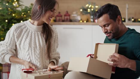 multi ethnicity couple opening christmas presents at home and having fun.