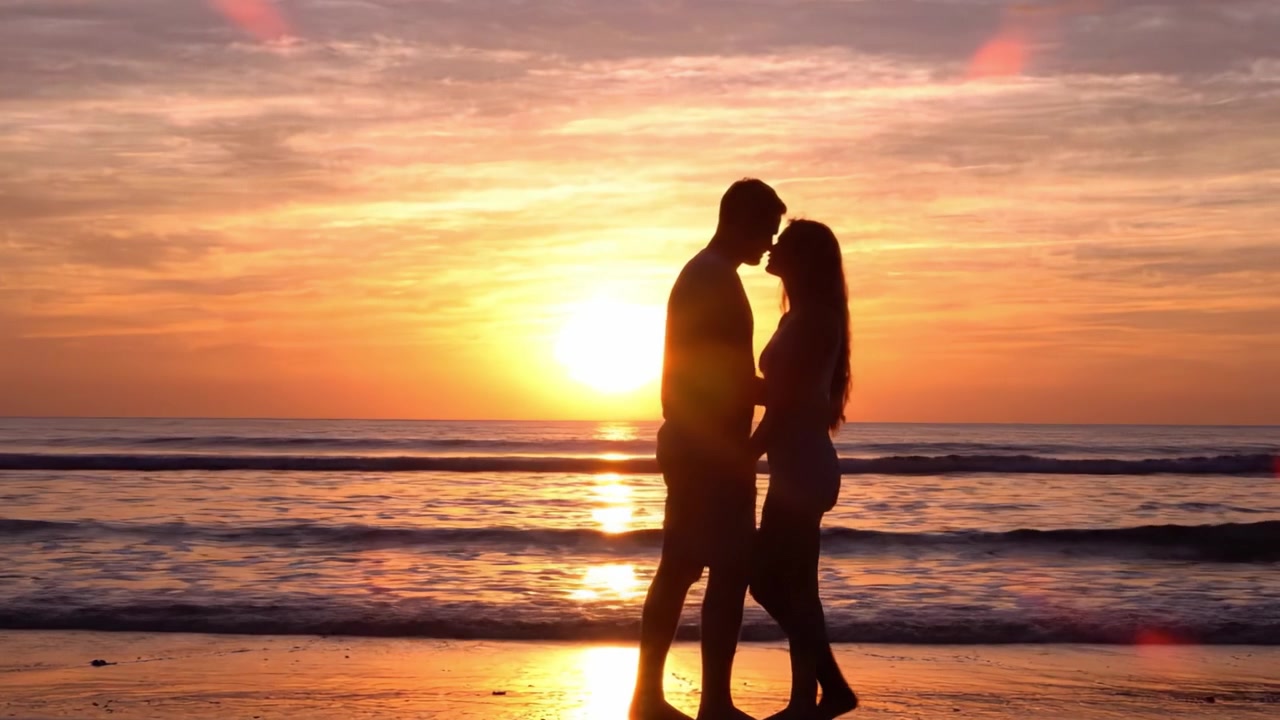 Un tramonto romantico sull'oceano: una coppia che si abbraccia mentre il sole tramonta all'orizzonte, catturando un momento intimo di amore e connessione