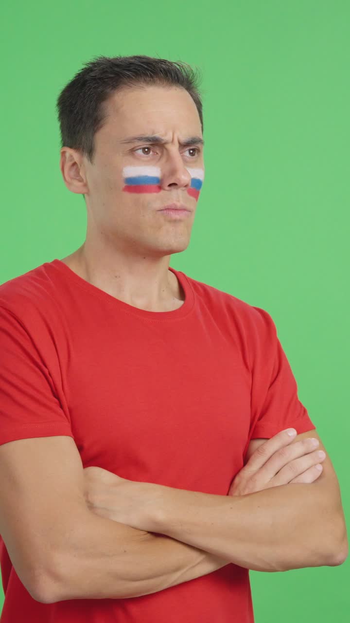 Mand med malet russisk flag, der kigger væk med et alvorligt udtryk
