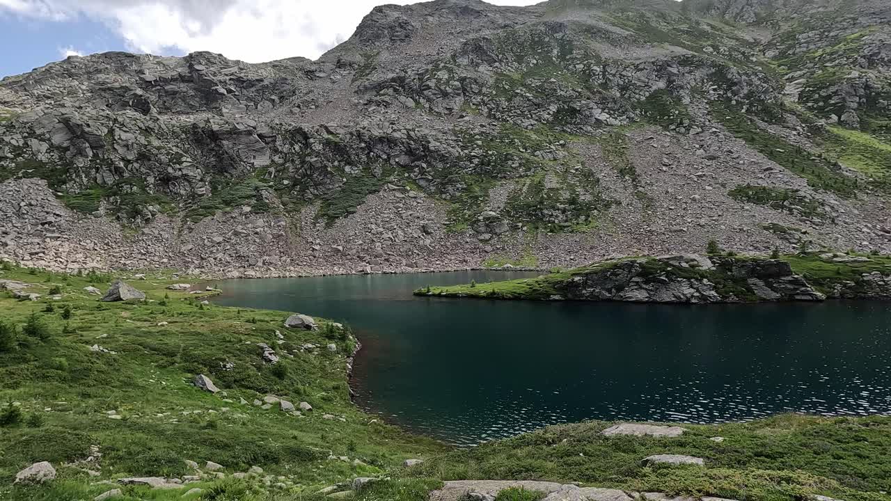 Pristine alpine lake Tschawinersee surrounded by rocky hills and peaks in Valais, Switzerland.