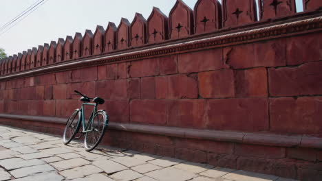 antique bicycle leaning against red stone wall