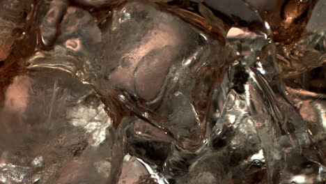 pouring cola on ice cubes extreme close-up