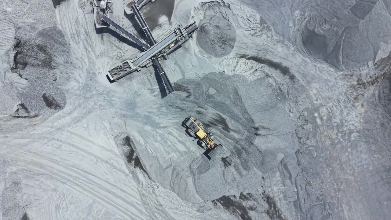 Work takes place at a granite quarry site with machinery moving and processing materials during daytime hours