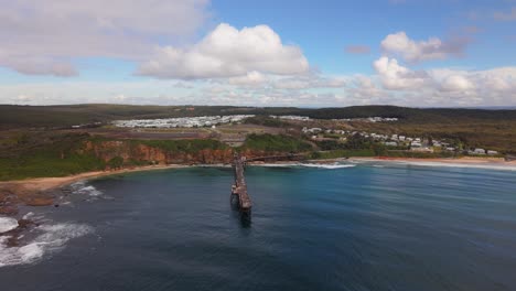 wide aerial of catherine hill bay ocean waters and jetty stretching out in new south wales, orbit approach