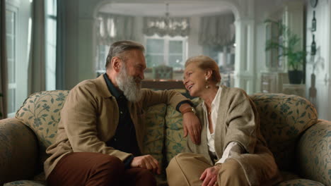 happy elderly couple laughing in cozy living room