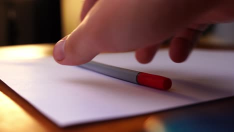 red pen for marking is put on a table and taken away again on a white paper