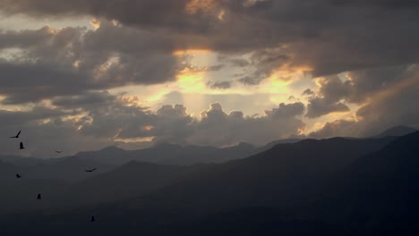 sunset with sunrays with silhouetted birds gliding around in the andes mountains