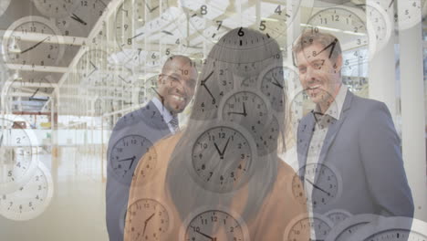 clocks animation over diverse business people discussing in modern office