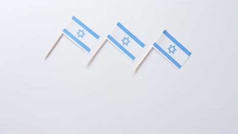 Close-up-of-three-flags-of-israel-lying-on-white-background-with-copy-space