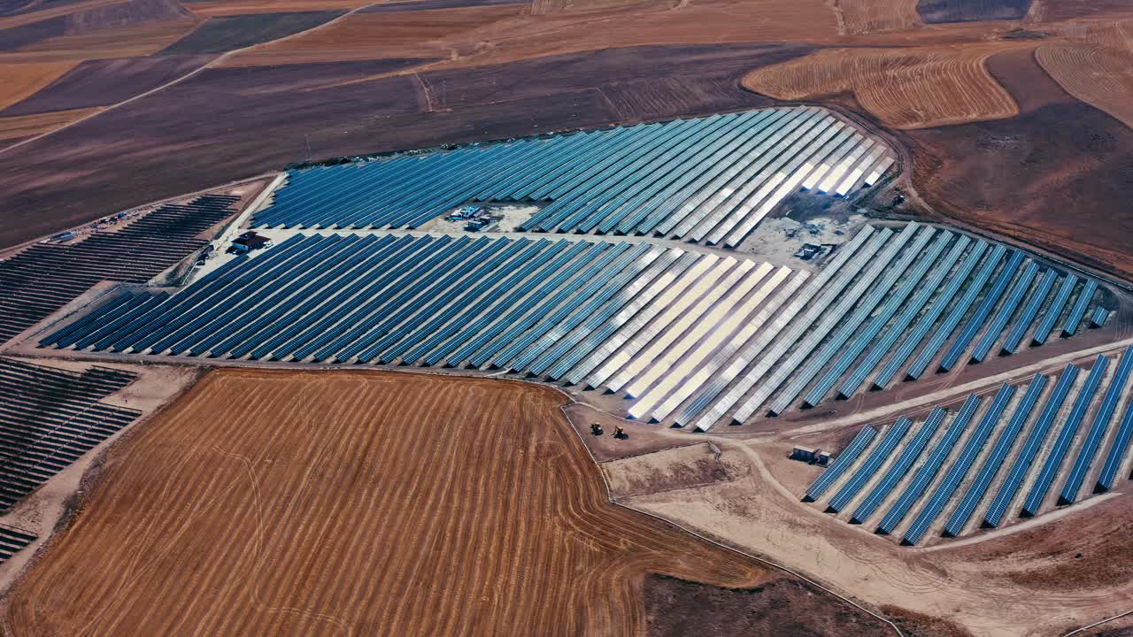 una impresionante vista aérea de una granja solar a gran escala en un paisaje seco, que muestra filas de paneles solares que generan energía limpia y renovable