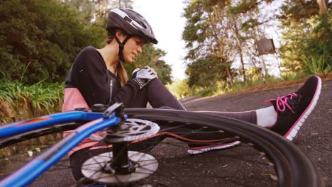 Ciclista-De-Montaña-Femenina-Sentada-En-El-Suelo-Con-Dolor