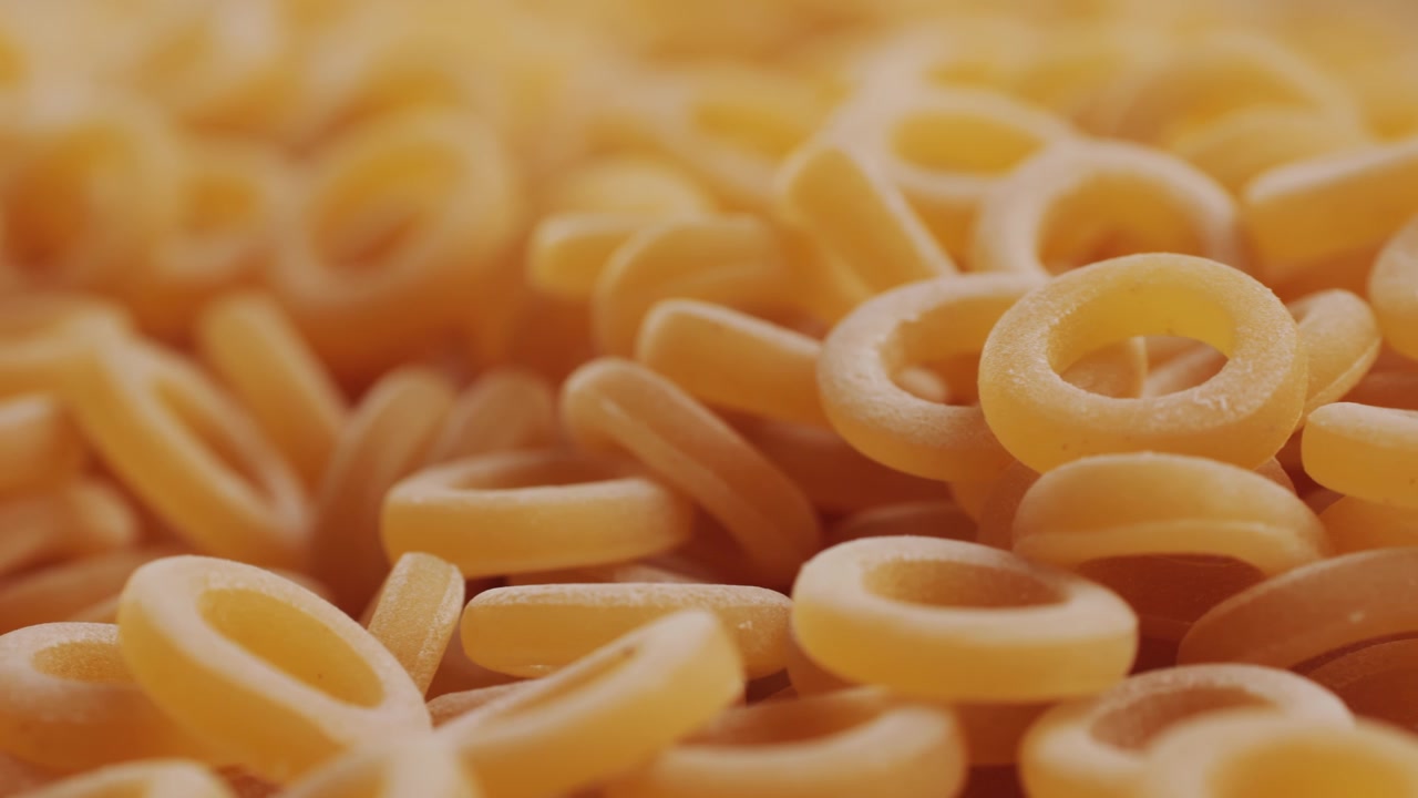 Pasta integrale biologica, maccheroni di semola di grano duro, penne rigate crude in una ciotola di legno. Filmato 4k di alta qualità