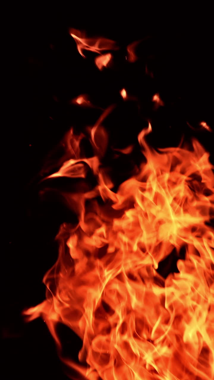 Hot red flame striving up in the air horizontally and vertically. Beautiful flame dancing in the darkness. Vertical video