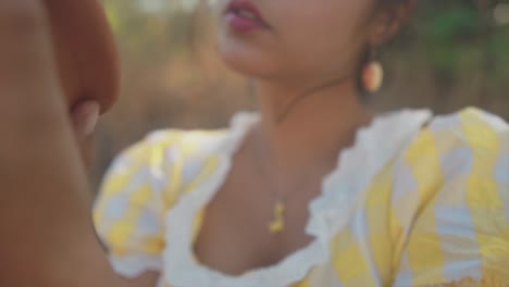 a close up shot of the face of an attractive young asian female admiring a clay pot as she looks closely at the details on a sunny day outdoors, india