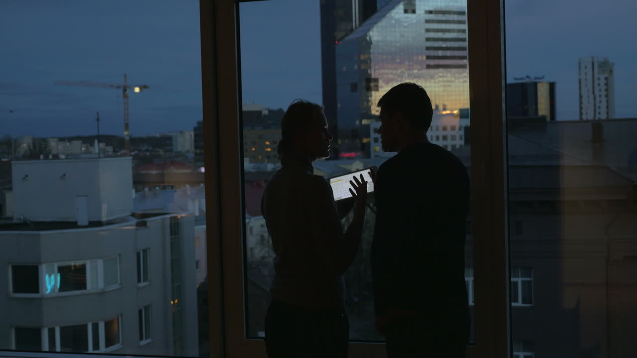 Pareja usando una tablet y disfrutando de la vista de la ciudad al atardecer