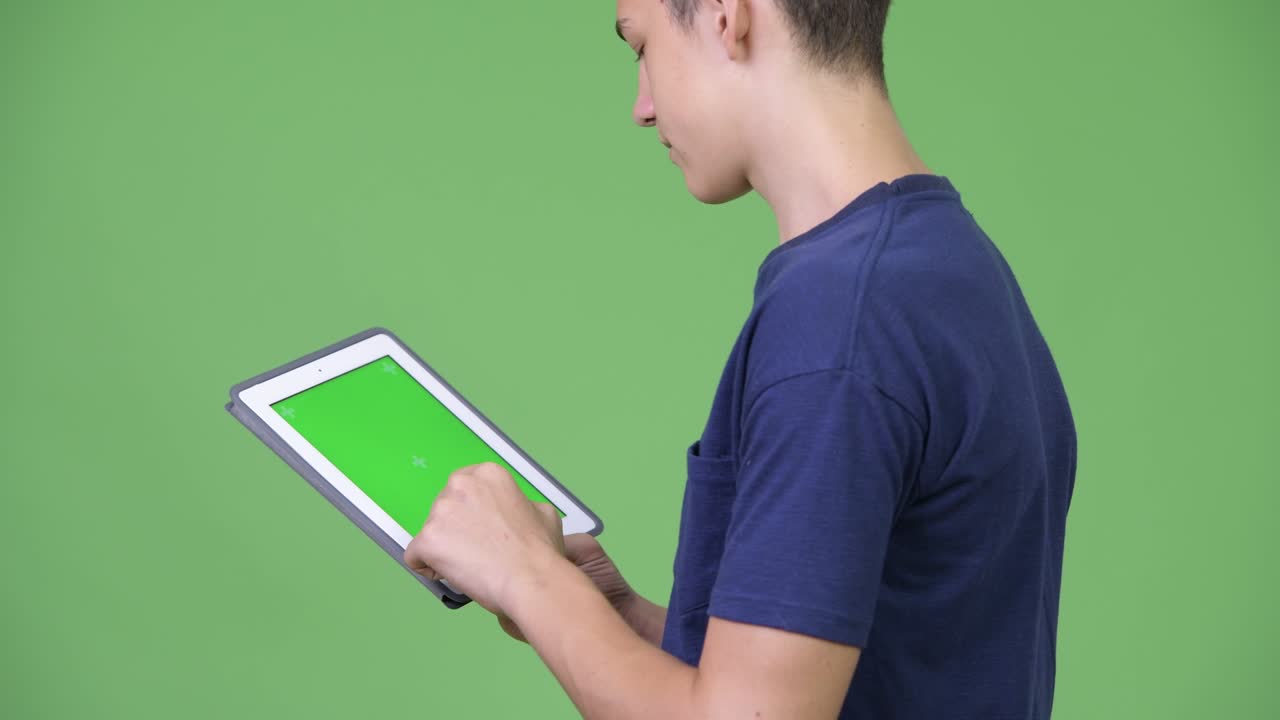 Young handsome teenage boy using digital tablet