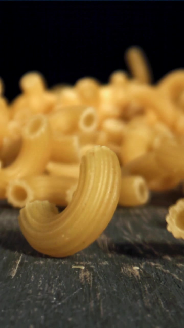 Primo piano estremo di maccheroni crudi su una superficie scura