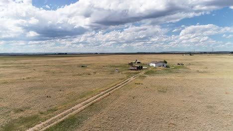 a dropping altitude shot of a small farm house on the great plains of north america