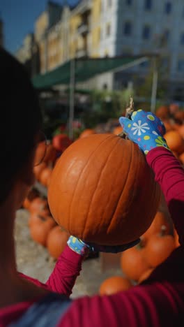 mujer sosteniendo una calabaza en un mercado al aire libre