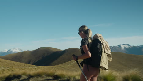 mujer en forma usando bastones de marcha nórdica subiendo senderos de montaña en un día soleado