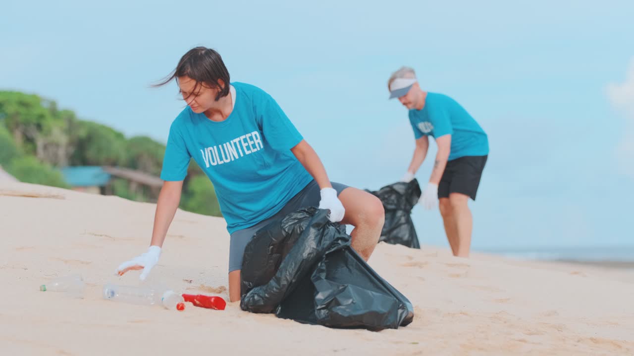 Young caucasian ecoactivists raise plastic garbage from sea beach