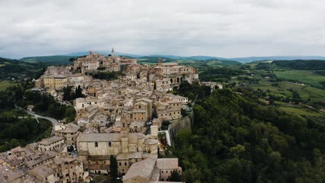 Wide-aerial-view-of-Tuscany,-Italy-with-a-city-surrounded-by-a-green-forest