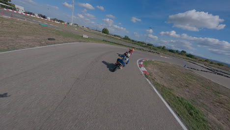 Dynamic-FPV-drone-POV-circling-around-motorcycle-riders-twisting-racing-circuit,-Aerial-view