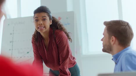 mujer africana regañando a colegas emocionales en la sala de reuniones