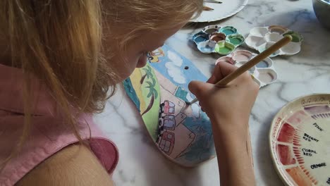 child painting a ceramic plate