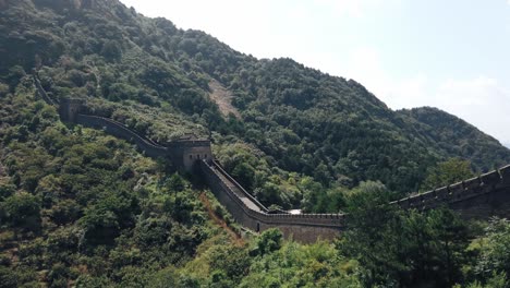 a panoramic view of the great wall of china, showcasing its historic architecture amidst lush green mountains and a clear sky.